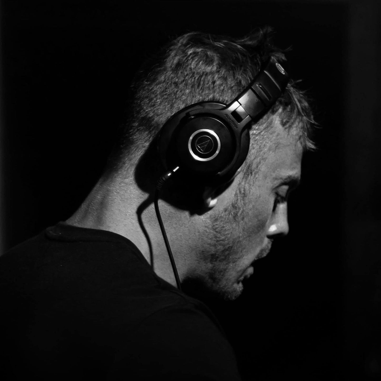 James Mackie DJing, headphones on, in profile